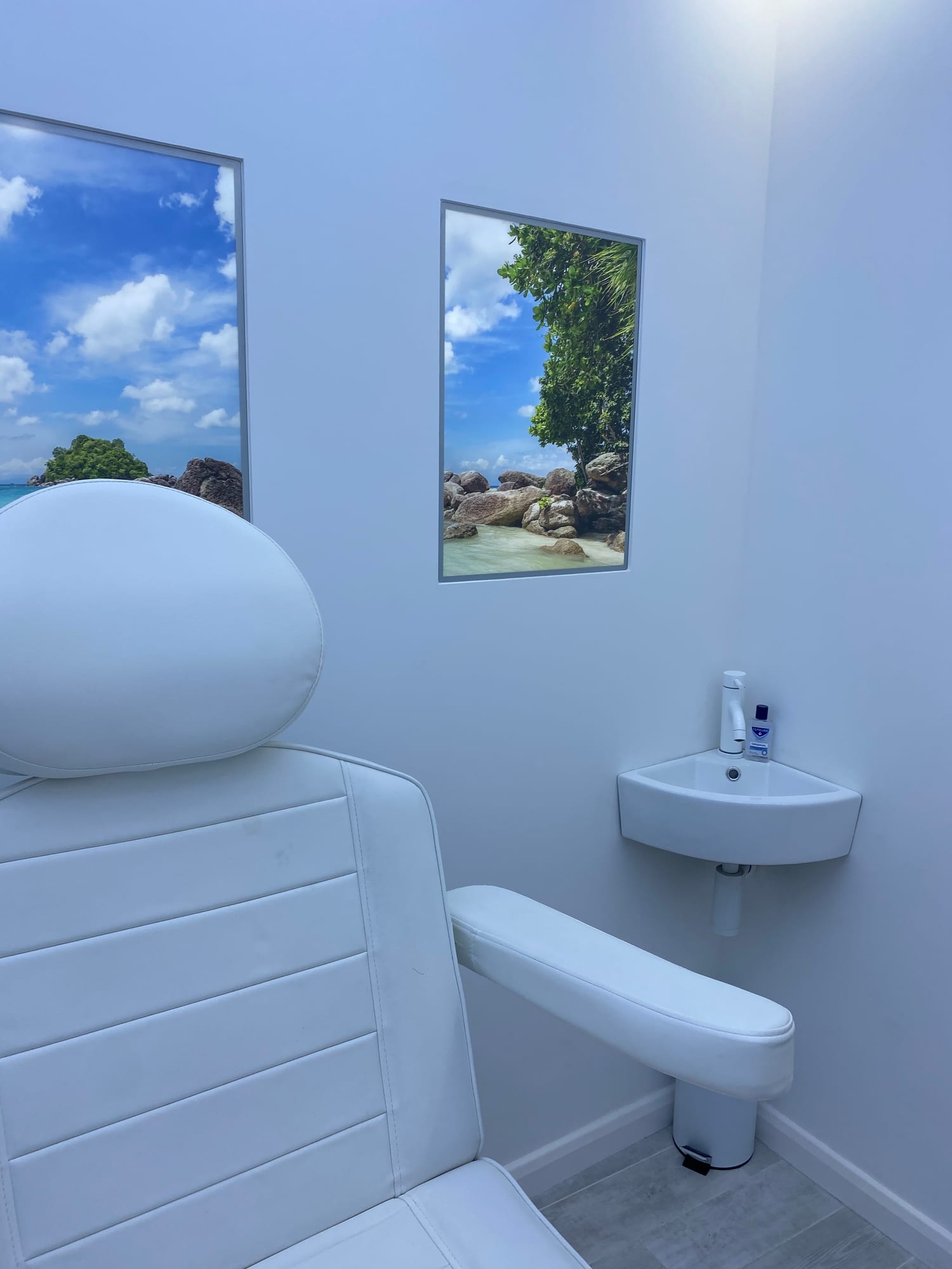 Treatment chair and sink in the clinic with framed beach pictures