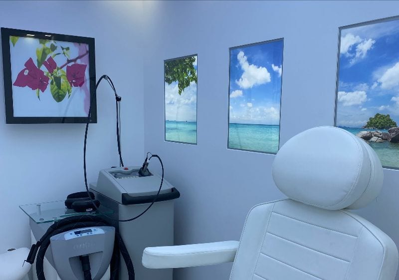 Laser treatment room with a white treatment chair and framed beach pictures