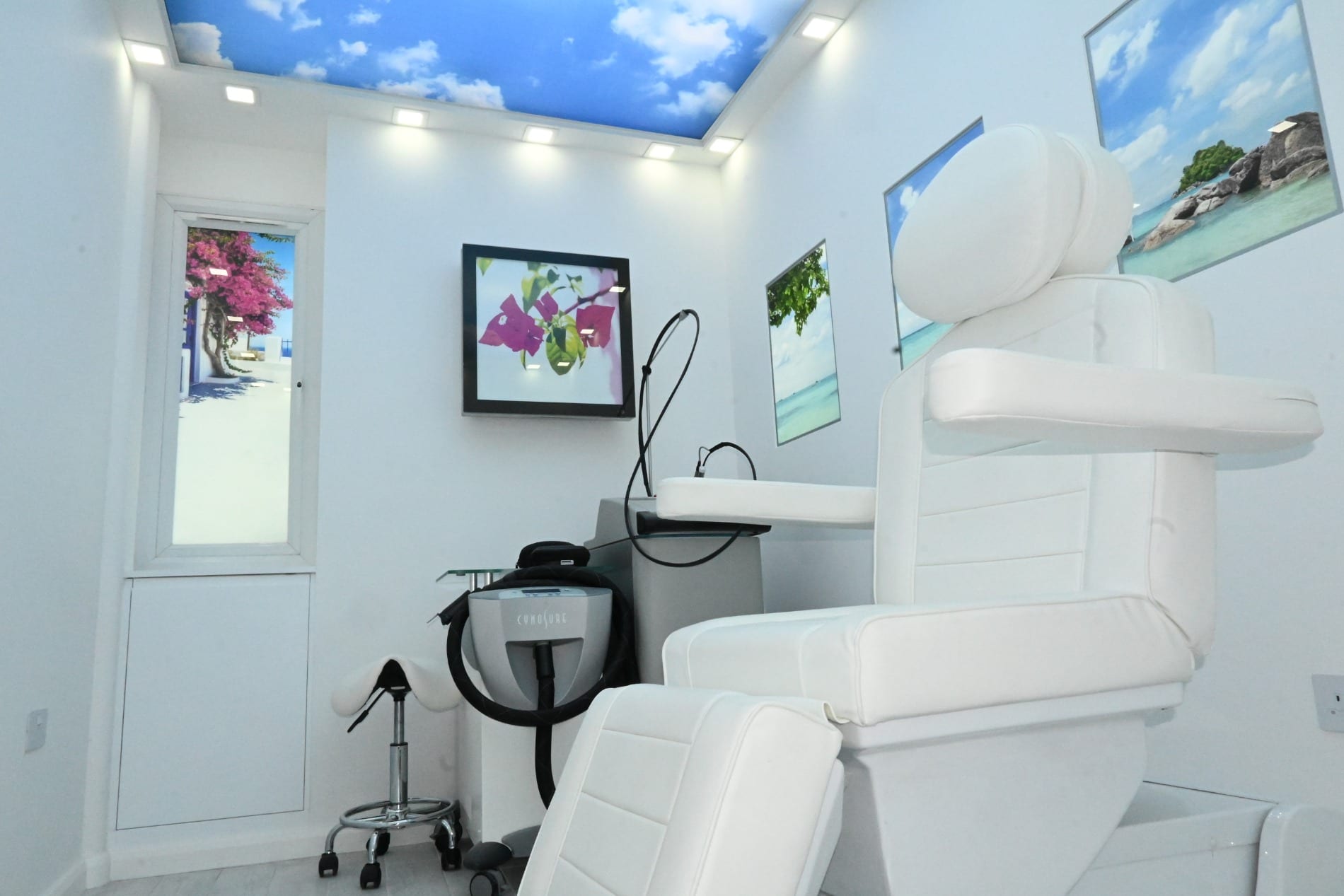 Treatment room with laser equipment, a white chair and framed pictures