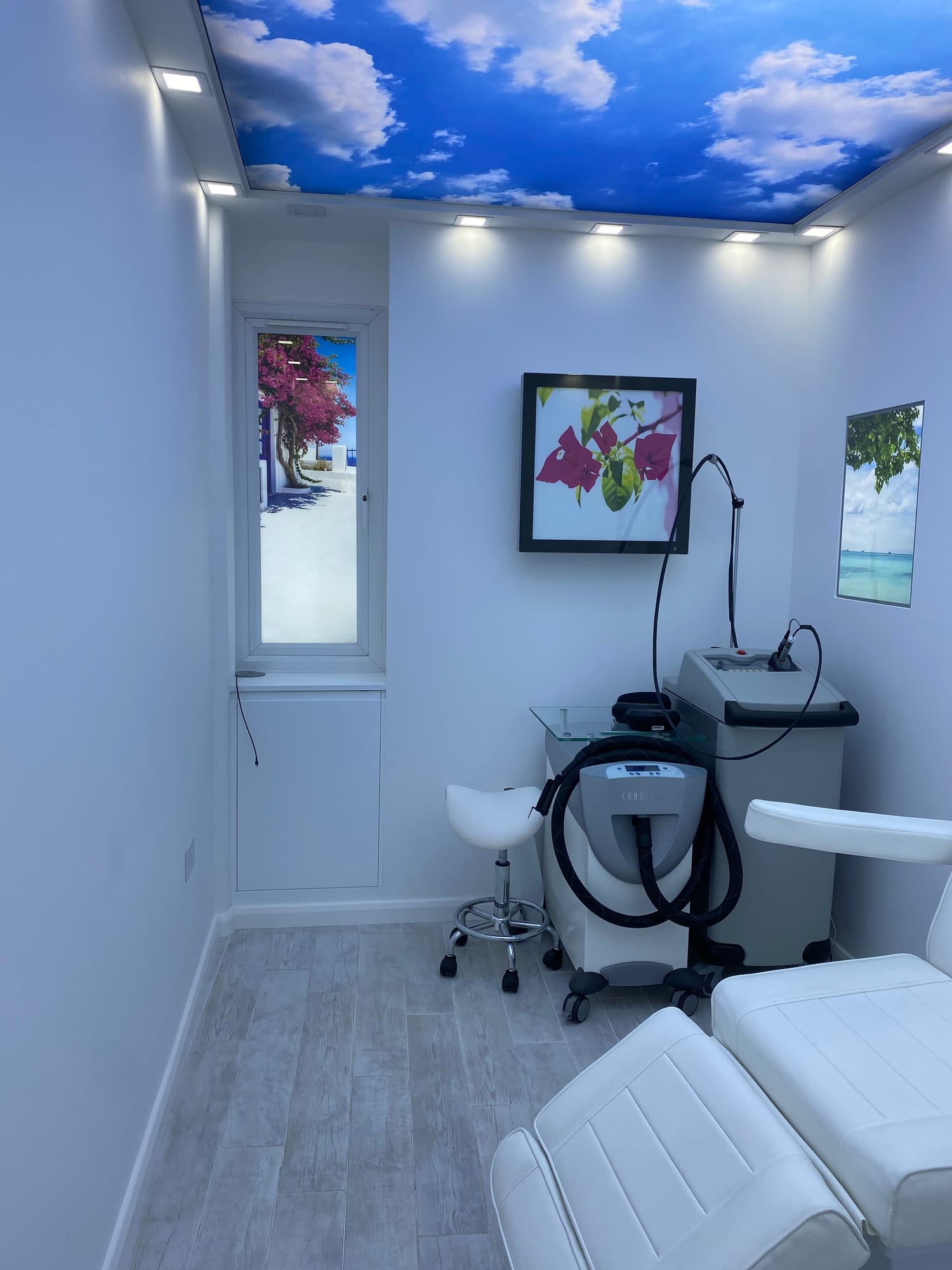 Laser treatment room with a treatment chair, laser machine and a blue sky ceiling panel