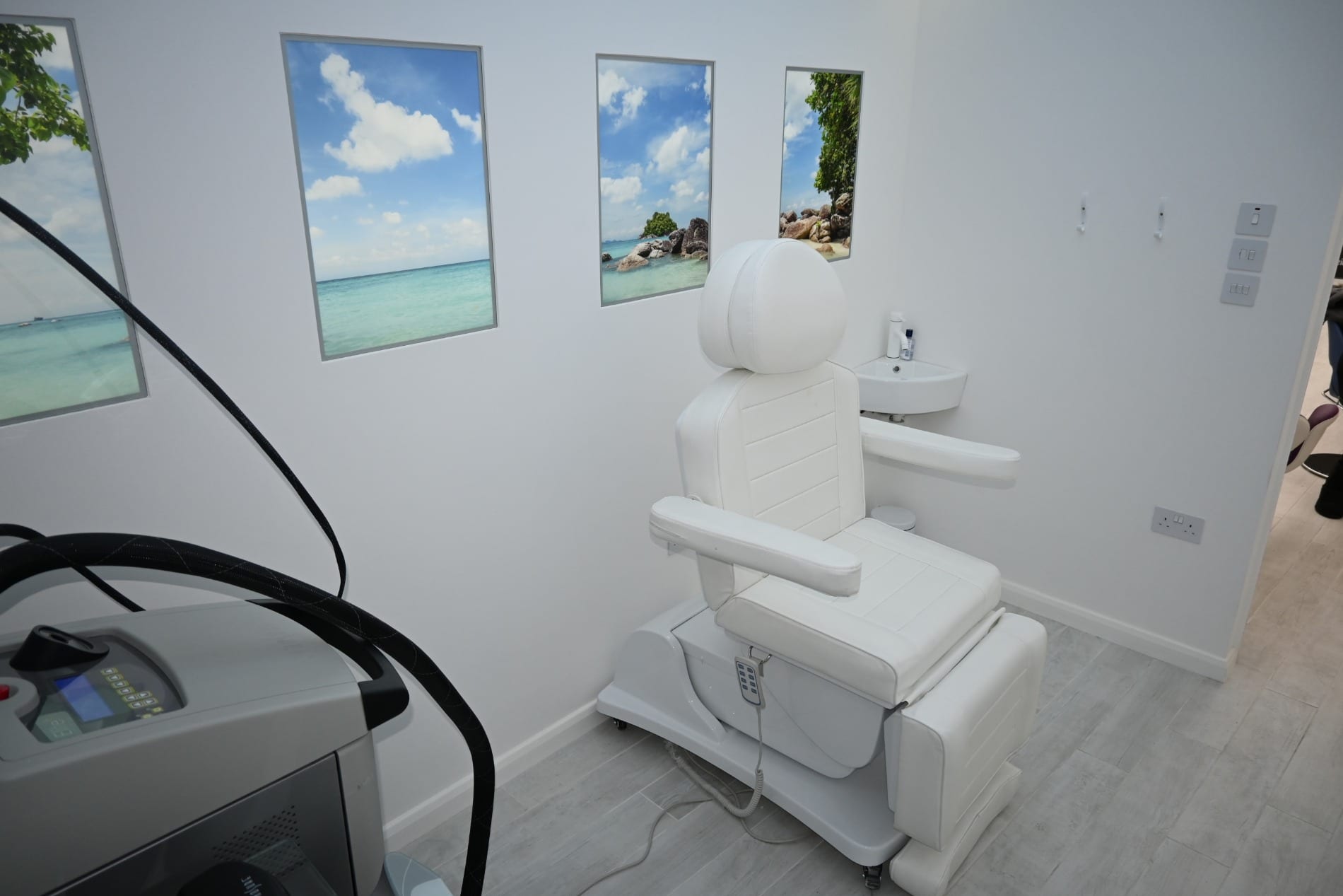 Clinic treatment room with a white treatment chair and framed beach pictures