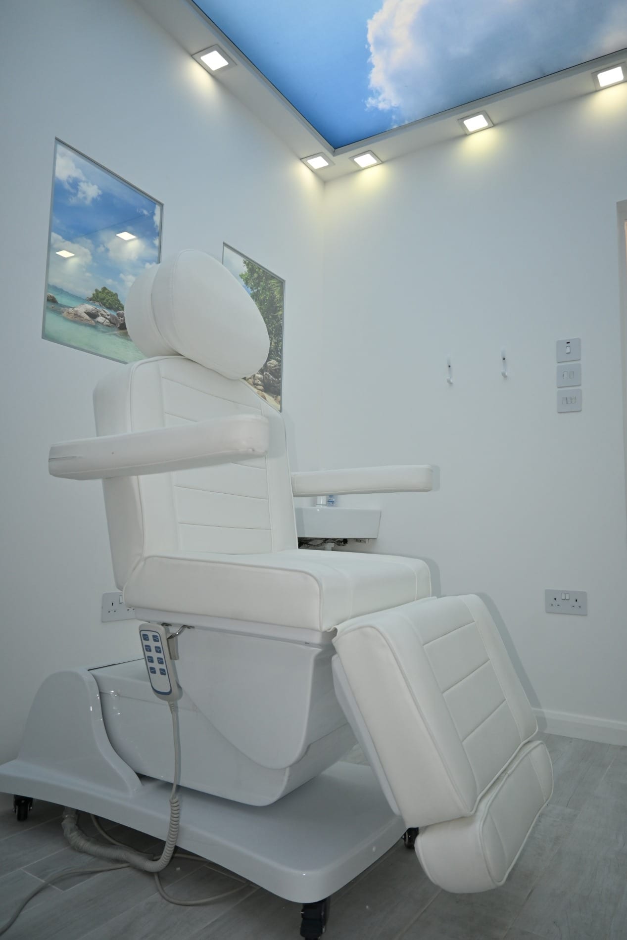 Reclining white treatment chair under a blue sky ceiling panel